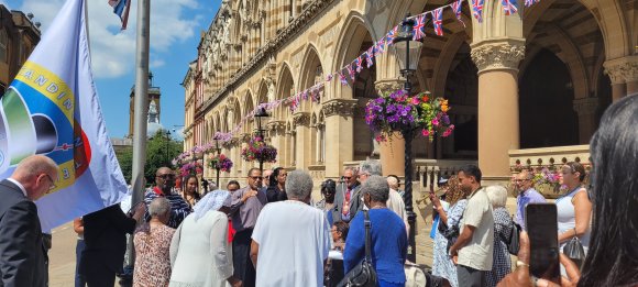 Crowds gather for the raising of the Windrush National Standard